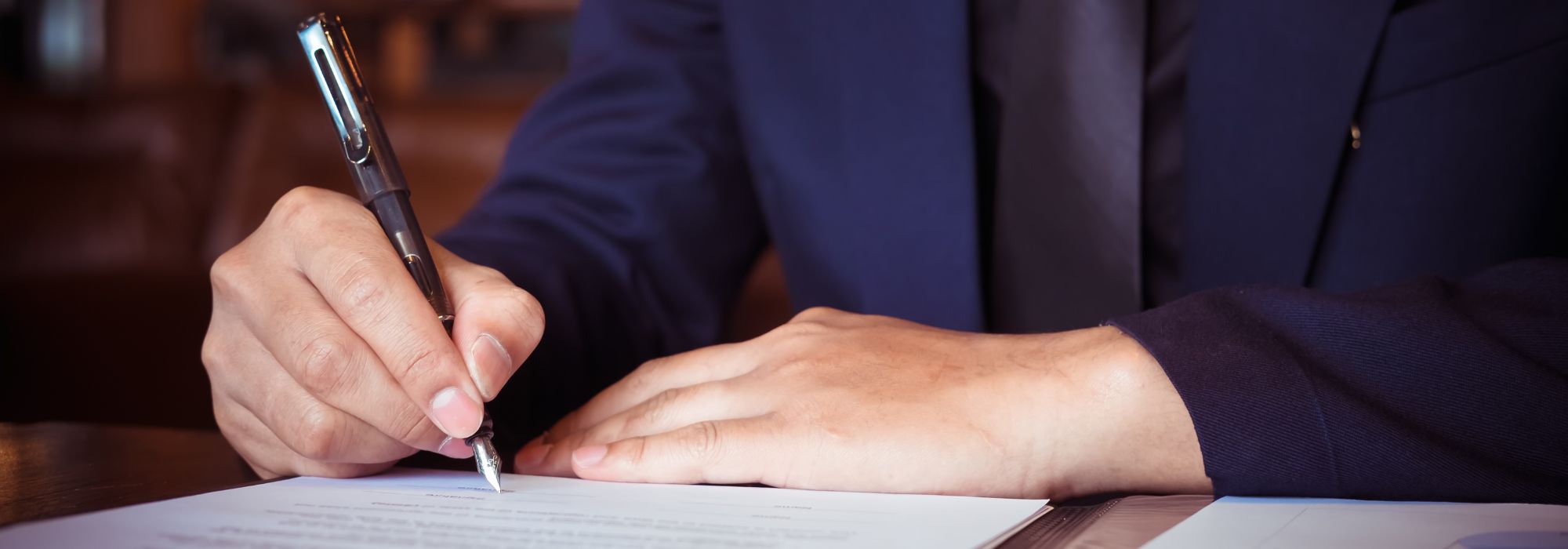 Man in a suit writing on a notepad