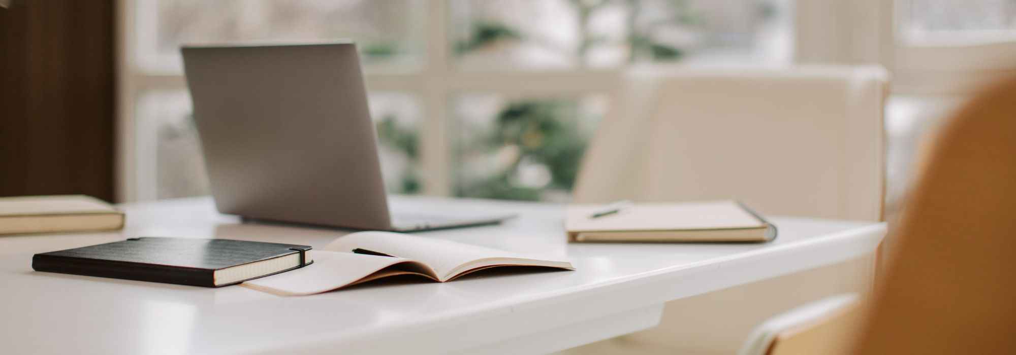 Picture of a laptop and notebooks on a desktop.