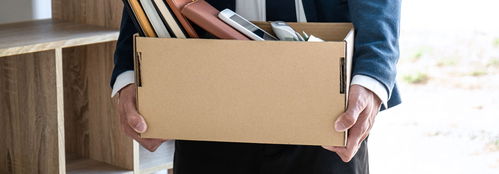 Person carrying a box full of books and office supplies