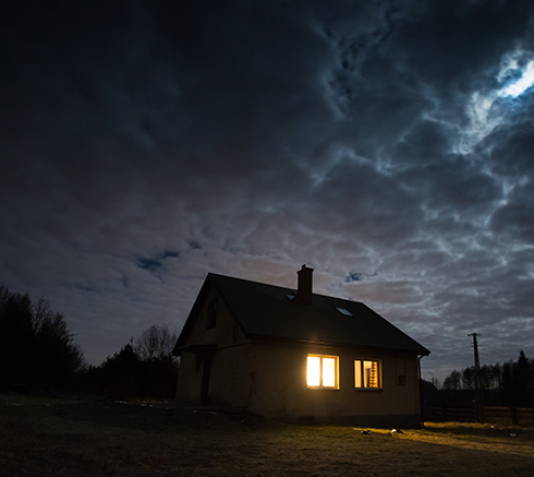 Landscape with house at night under cloudy sky