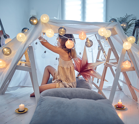 Little girl playing and making a house tent in the room.