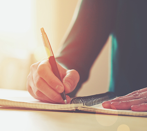 female hands with pen writing on notebook