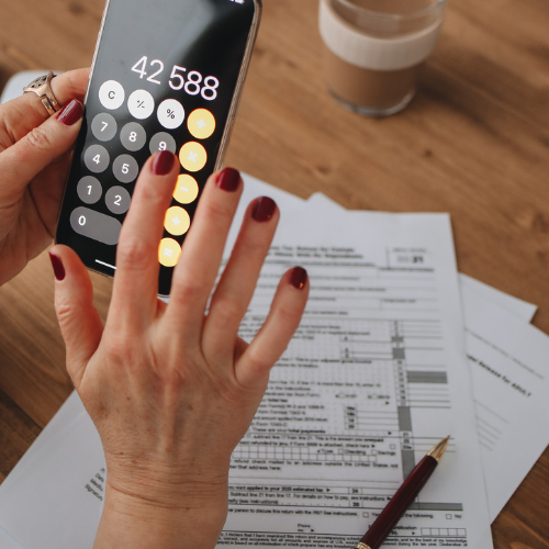 Photo of a person using a calculator over a stack of paperwork