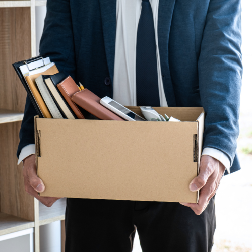 Person carrying a box full of books and office supplies