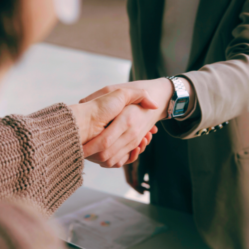 Photo of two people shaking hands over a document